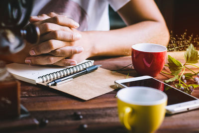 Close-up of man preparing coffee cup on table