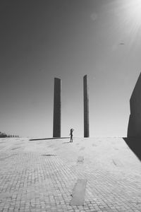 Woman walking by built structure against clear sky