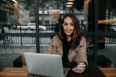 Portrait of smiling young woman using smart phone