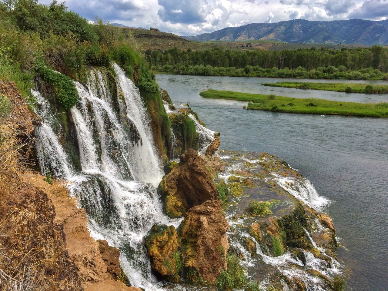 water, mountain, scenics, beauty in nature, flowing water, flowing, nature, tranquil scene, waterfall, river, tranquility, motion, stream, rock - object, landscape, non-urban scene, idyllic, grass, sky, day