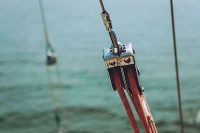 Close-up of rope tied with cable on pulley at sailboat