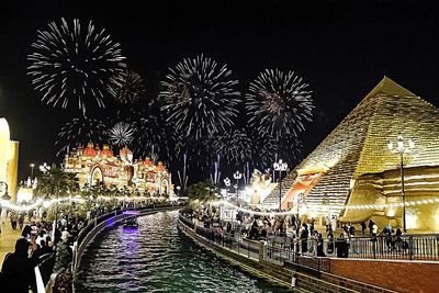 Firework display in city against sky at night