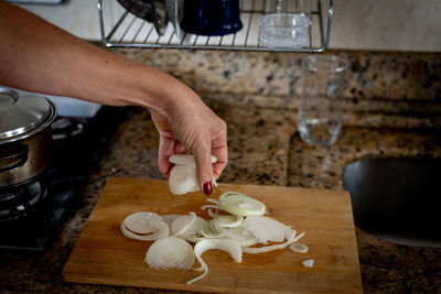 Hand holding sliced onions on a cutting board. food seasoning.