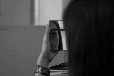 Cropped image of woman reflecting in mirror while applying eyebrow pencil