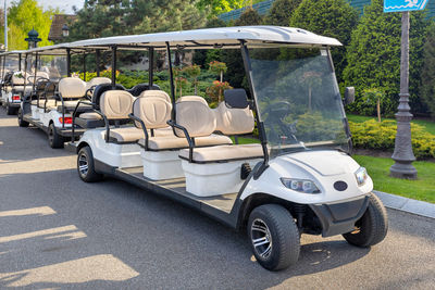 Golf cars parked at the edge of the lawn in the rays of the setting sun.