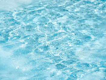 Sun beams on surface of water in fountain with blue mosaic bottom.  pattern of transparent water.