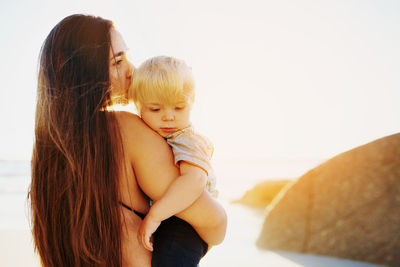 Mother and son at beach against sky