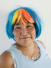 Portrait of smiling mature woman wearing wig against wall