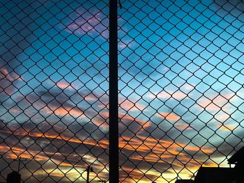 Full frame shot of chainlink fence against sky during sunset