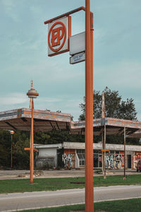 Information sign on road by building against sky
