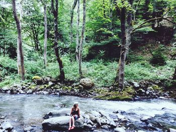 Full length of woman standing by stream in forest