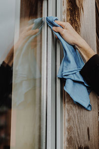 Cropped hand of cleaner cleaning glass window