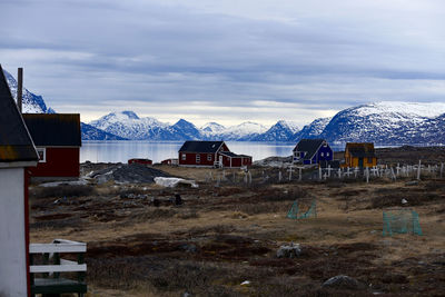 Houses at lakeshore against cloudy sky during winter