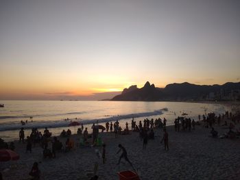 People on beach against sky during sunset