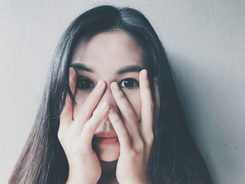 Portrait of young woman with hands covering face