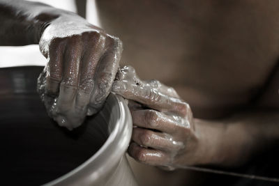 Cropped image of person molding shape on pottery wheel