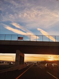 Bridge over road against sky during sunset