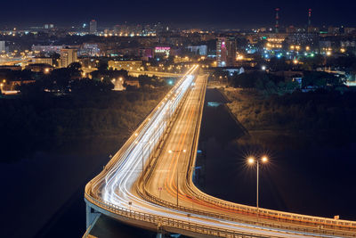 High angle view of light trails on street amidst buildings at night