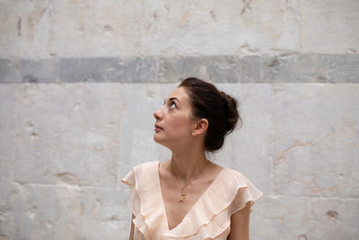 Beautiful women looking up while standing by wall