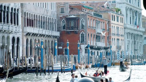 People in gondola on grand canal by buildings