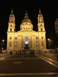 People at illuminated cathedral against sky at night