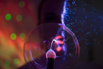 Close-up portrait of young woman against illuminated background