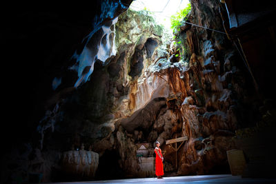 Rear view of woman standing in cave