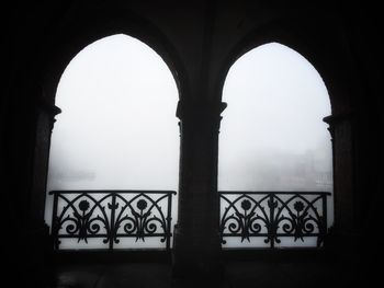 Silhouette of building against clear sky seen through window