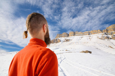 Rear view of man standing on snow covered mountain against sky