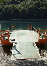 Boat moored on pier by lake