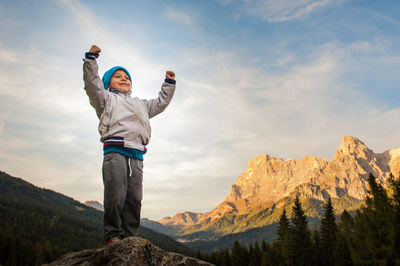 Low angle view of smiling standing on mountain against sky