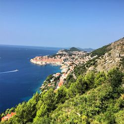 High angle view of townscape by sea against clear blue sky