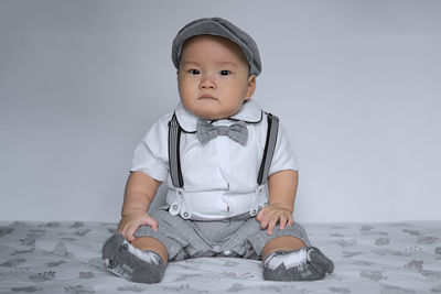 Portrait of cute boy sitting against wall