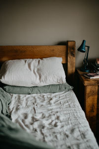 Morning scene of crumpled linen sheets and duvet bedding on wooden bed