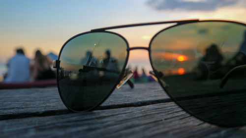 Close-up of sunglasses on table against sky during sunset