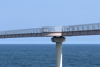 Bridge over sea against clear blue sky