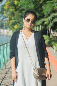 Portrait of young woman wearing sunglasses standing outdoors