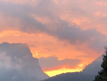 Low angle view of silhouette mountains against orange sky