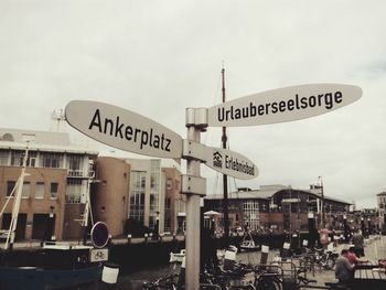 Close-up of information sign in city against sky