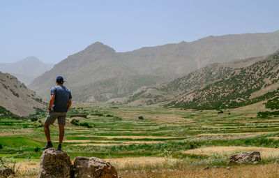 Rear view of man looking at mountains against sky