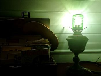 Close-up of illuminated lighting equipment on table against wall