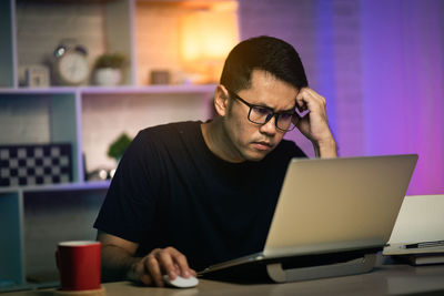 Man using mobile phone while sitting on table