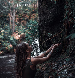 Woman standing by tree trunk in forest