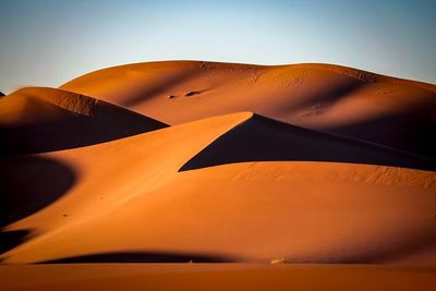 Low angle view of sand dunes against clear sky