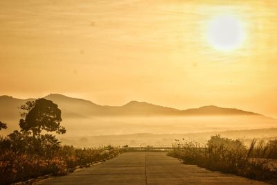 Road leading towards mountains against sky during sunset