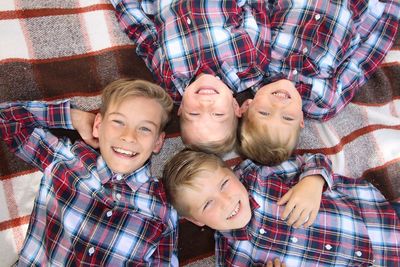 Close-up portrait of smiling boys lying on blanket