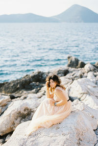 Young woman sitting on rock at beach