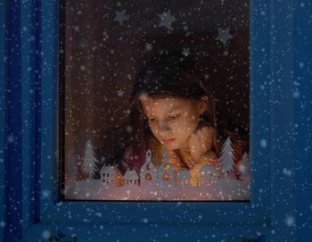 Close-up of girl looking through window