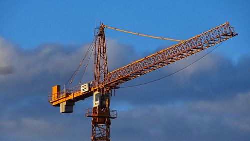 Low angle view of crane against sky