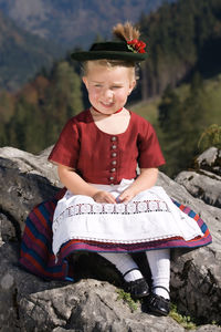 Full length of cute girl sitting on rock